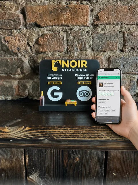 A phone being tapped against an NFC display on a wooden table